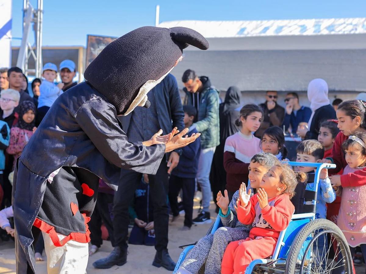 A performer entertains children at a Jawwal event in a displacement camp